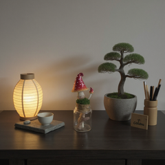 Decorative items on a table including a lit lamp, gnome figure, bonsai tree, and 'calm' card.
