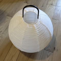 White paper lantern with a black handle on a wooden floor