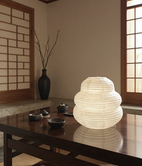 White paper lantern on a wooden table in a room with a traditional Japanese sliding door.